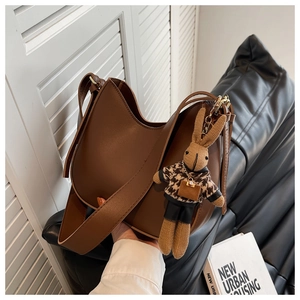 Detail view of brown leather hobo bag with gold hardware and knit bunny charm