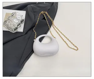 Dettaglio mini borsa ovale in acrilico bianco con manico rotondo e catena d'oro