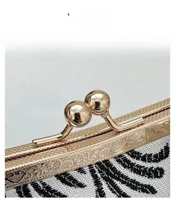 Detail view of vintage gold floral engraved frame and metal clasp on embroidery bag