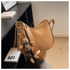 Close-up of minimalist khaki crescent bag featuring a stylish plaid bunny charm