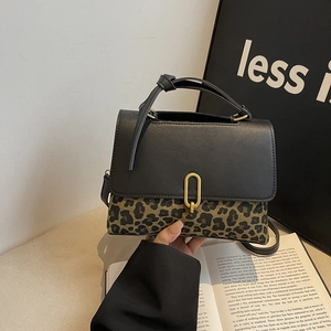 Leopard print crossbody bag with black leather flap and gold metal clasp on a book