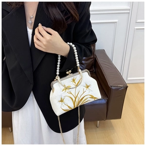 Detail of vintage embroidered clutch with pearl handle and golden chain strap for women