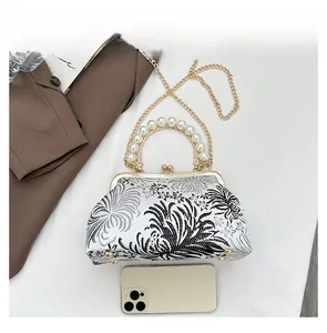 Close-up of white floral embroidery bag with pearl handle and metal chain for size check