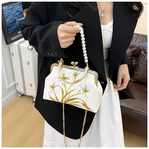 Detail of floral embroidery and pearl handle on a vintage-style cream evening bag