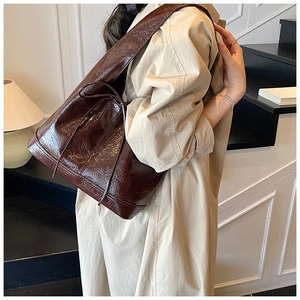 Close-up of dark brown glossy patent leather shoulder bag with a vintage waxed texture