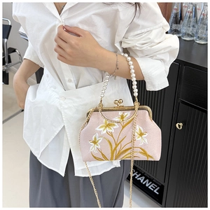 Detail of pink embroidered floral pattern and elegant pearl handle on a retro handbag