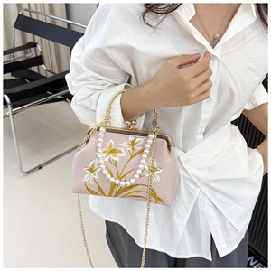 Detail of vintage pink embroidered handbag with metal handle and pearl strap detail