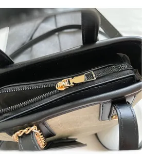 Nahaufnahme von goldenem Metallreißverschluss und schwarzem Lederbesatz an Stofftasche