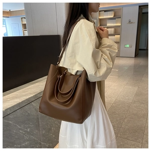 Détail d'un sac cabas marron foncé sur marbre avec texture cuir et grande capacité de rangement