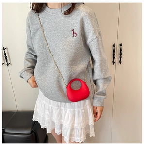 Dettaglio mini borsa rossa con silhouette arrotondata e tracolla a catena dorata sottile