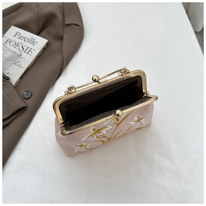 Detail of vintage floral embroidery and pearl chain on a pink velvet evening bag