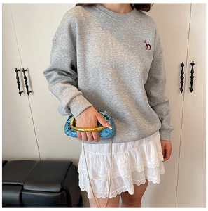 Detail of grey crewneck sweatshirt with red puppy embroidery and layered lace skirt