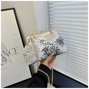 Detailed shot of vintage gold kiss-lock closure and floral embroidery on a white fabric bag