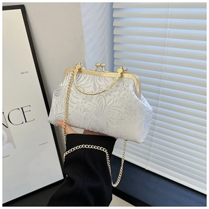 Detail of white floral jacquard evening bag with golden ring handle and metal chain
