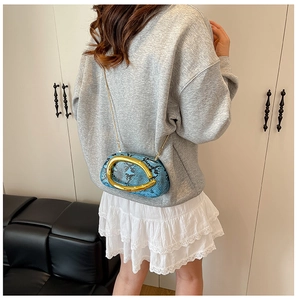 Blue snake skin crossbody bag with large gold U-buckle on a stylish outfit