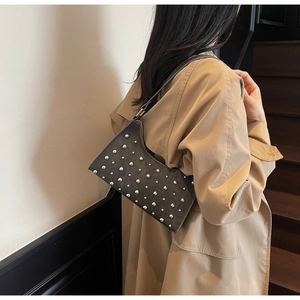 Détail du sac à main gris foncé avec rivets argentés et bandoulière en cuir mat