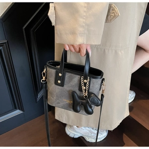 Detail einer grauen Segeltuchtasche mit Ledergriffen und einem Ballon-Hund-Anhänger