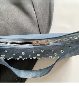 Détail de la fermeture éclair et des rivets argentés sur sac en denim bleu clair