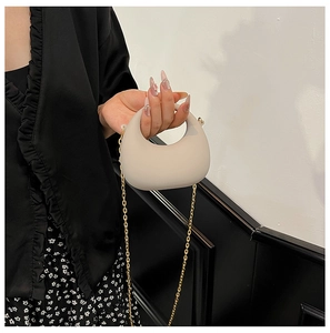Dettaglio della mini borsa a mezzaluna bianco sporco con catena dorata sottile