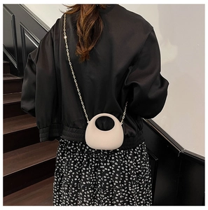 Dettaglio della borsa in acrilico beige minimalista con catena dorata su modella