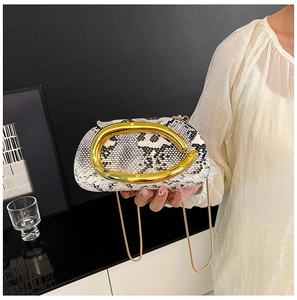 Detail of snake skin print clutch featuring a bold gold metal handle and chain strap