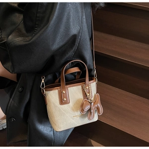 Detail der Canvas-Leder-Tragetasche mit Bärenanhänger, präsentiert von einem Model