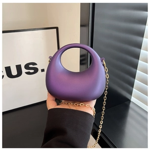 Dettaglio borsa a mano semicircolare in acrilico viola con tracolla a catena oro