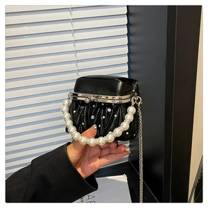 Close-up of pleated leather bag with pearl handle and rhinestone details