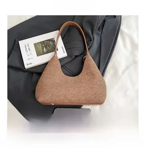 Brown textured hobo bag detail with metal studs next to a smartphone for size reference