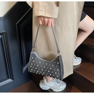 Vue détaillée du sac demi-lune en daim gris foncé avec rivets porté sur un escalier