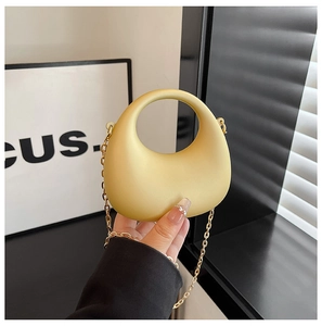 Dettaglio della borsa in acrilico giallo chiaro con manico circolare e catena in metallo dorato