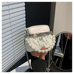 Close-up of white quilted handbag with pearl handle and vintage metal clasp detail