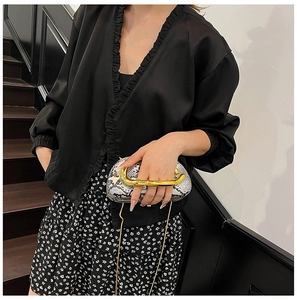 Detail of snake skin pattern handbag with iconic gold C-shaped metal top handle