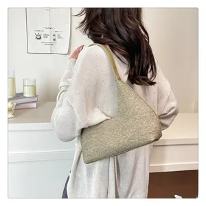 Model view of grey-green textured wool underarm bag with minimalist half-moon shape