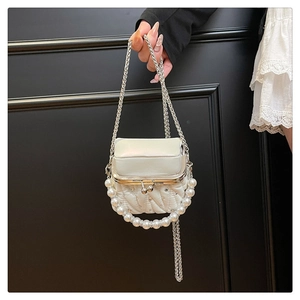 Detailed view of quilted cream bag with pearl handle and rhinestone chain
