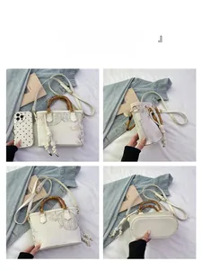 Detail view of floral embroidery bucket bag with bamboo handle and leather strap