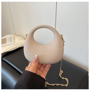 Dettaglio della borsa beige a mezzaluna con manico rotondo e catena in metallo dorato