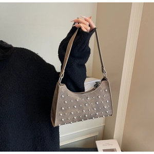 Détail du sac sous le bras marron avec rivets argentés et forme en croissant vintage