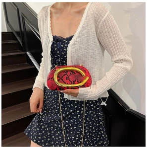 Detail of red snake pattern clutch with gold C-shaped metal handle and chain strap
