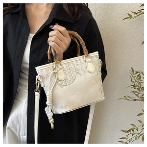 Detail of vintage bucket bag with bamboo handle and elegant floral embroidery textures