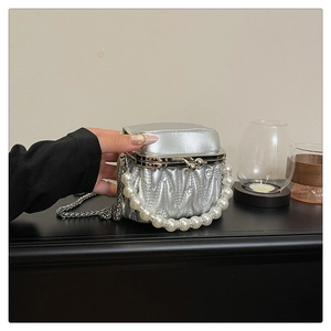 Close-up of silver pleated mini bag featuring a pearl handle and chic metal chain strap