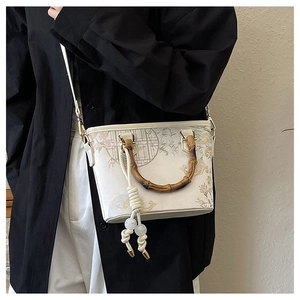 Detail of embroidered bucket bag with natural bamboo handle and floral pattern print