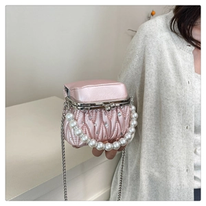Detailed view of pink pleated satin handbag with rhinestone accents and pearl handle chain