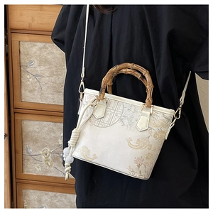 Detail of vintage bucket bag with bamboo handle and elegant floral embroidery