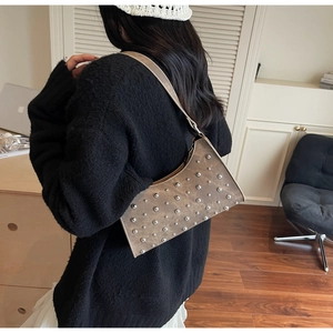 Sac à bandoulière marron à rivets avec texture vintage porté dans un décor domestique