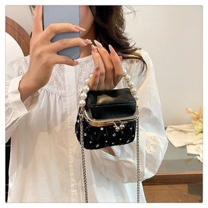 Detail of black quilted mini bag with pearl handle and crystal studs on metal clasp