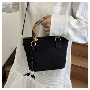 Detail of vintage bucket bag with bamboo handle and gold hardware on white dress
