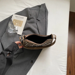 Détail intérieur du sac en daim marron avec fermeture éclair et rivets argentés