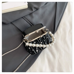 Close-up of black pleated evening bag with rhinestone detail and pearl handle