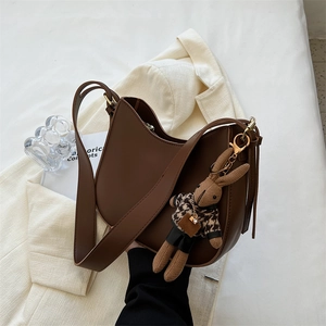 Deep brown matte hobo bucket bag with leopard bunny charm on a cream blazer